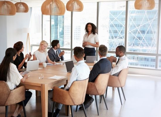 staff meeting with woman standing and leading meeting