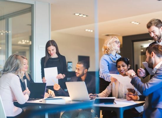 team at work collaborating at conference table on laptops team at work collaborating at conference table on laptops